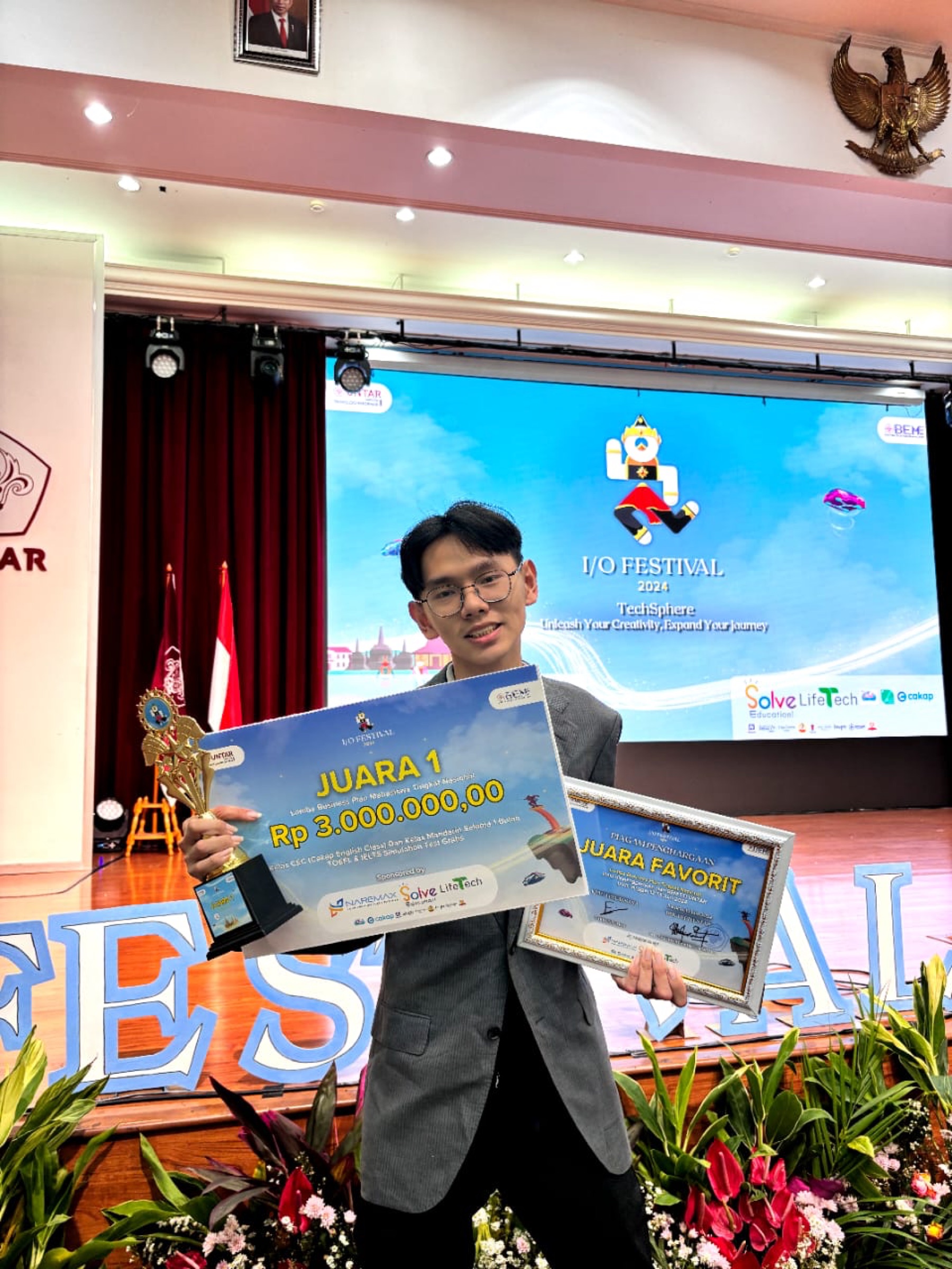 Richard memegang piala Juara 1 I/O Festival 2024 UNTAR